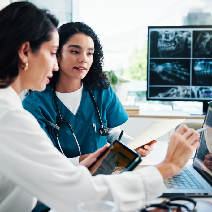 Medizinisches Team analysiert Patientendaten und Röntgenbilder digital am Laptop in einer modernen Praxis.