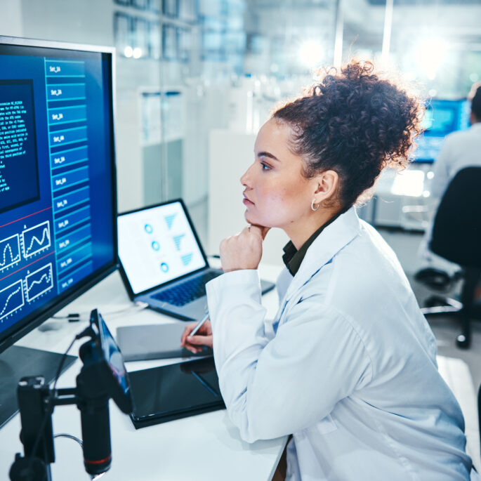 Forscherin analysiert medizinische Datenvisualisierungen und Diagramme auf einem großen Bildschirm in einem digitalen Labor für Gesundheits- und Medizintechnologie.
