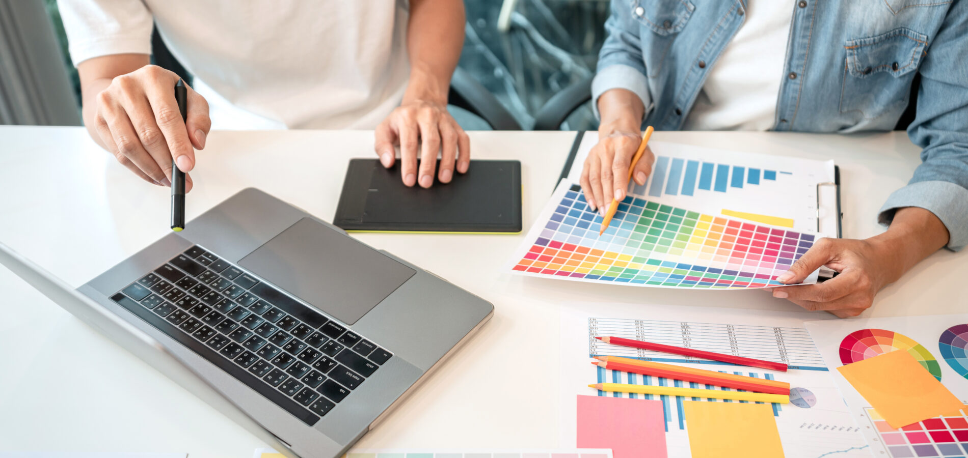 Zwei Designer arbeiten am Laptop und nutzen Farbpaletten für ihr kreatives Projekt