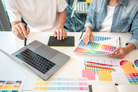 Zwei Designer arbeiten am Laptop und nutzen Farbpaletten für ihr kreatives Projekt