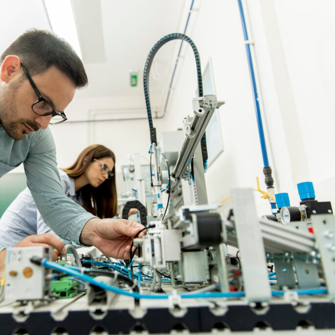 Techniker arbeitet an moderner Industrieanlage, eine Frau im Hintergrund