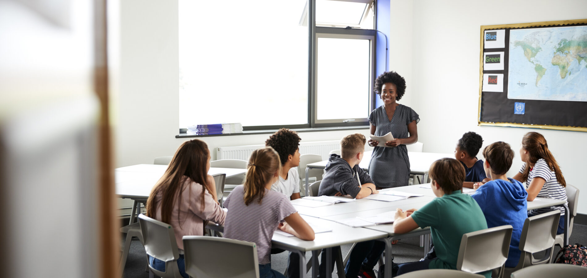 Lehrerin unterrichtet eine Gruppe von Schülerinnen und Schülern in einem modernen Klassenraum