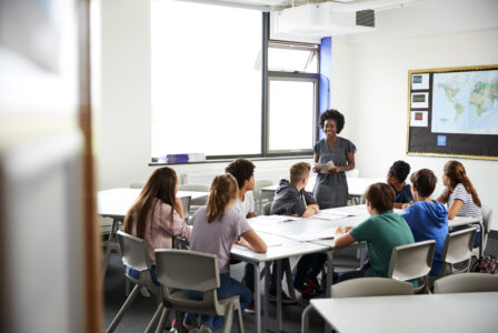 Lehrerin unterrichtet eine Gruppe von Schülerinnen und Schülern in einem modernen Klassenraum