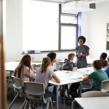 Lehrerin unterrichtet eine Gruppe von Schülerinnen und Schülern in einem modernen Klassenraum
